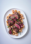 Ostrich steaks on lima beans with garlic and rosemary