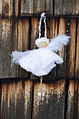 Handmade angel in white dress hung on wooden wall