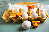 White eggs, muslin and yellow paper rosettes in yellow egg box
