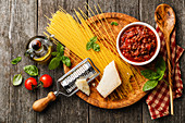 Zutaten für Spaghetti Bolognese auf Holzbrett und Holzuntergrund (Aufsicht)