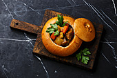 Beef meat soup Goulash stewed with potato, carrot and spices in Bread on black marble background