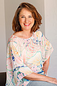 A brunette woman wearing a coloured blouse