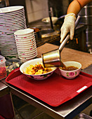 Nudelgericht in Restaurantküche servieren (Singapur)