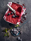 Blackberry sorbet with an ice cream scoop in a metal container