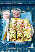 Spinach pancakes filled with eggs and smoked fish with red radishes and caviar sauce