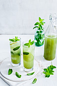 Two glasses with matcha iced tea, lime and mint leaves