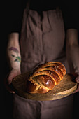 Frau hält Holzbrett mit Challah-Brot (jüdische Küche)