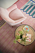Rosafarbener Sessel und Beistelltisch auf bunt gemustertem Teppich