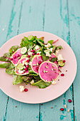 A salad with red chard, watermelon radish, feta cheese and pomegranate seeds