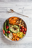 A Buddha bowl with bulgur, green asparagus, strawberries, carrots, tofu, tomatoes, sweetcorn, sweet potatoes and avocado