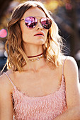 A young woman wearing sunglasses and a pink top