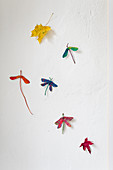 Dragonflies made from painted sycamore seeds on white wall