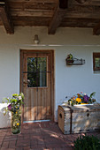 Autumn flowers in glass vase and arranged on wooden trunk next to front door