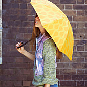 Junge Frau mit gelbem Regenschirm