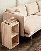 Side table made of wood next to an upholstered couch with a sand-colored cover