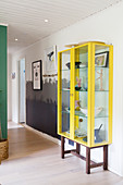Yellow display cabinet in hallway with wall painted in three shades