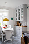 Pale grey dresser, white wooden table and chairs in kitchen-dining room