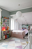 Bett mit Bettvorhang und Regale im Mädchenzimmer mit grauer Wand und Dachschräge