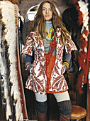 A young woman wearing a printed coat standing next to feather accessories