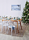 Festlicht gedeckter Tisch vor geschmücktem Weihnachtsbaum