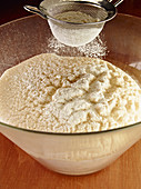 Dough for steamed, sweet yeast dumplings being dusted with flour