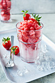 Strawberry granita in a cocktail glass with fresh strawberries and ice cubes