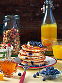 Pancakes with blueberries, maple syrup, butter and orange juice for brunch (USA)