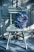 Kissen in Zapfenform aus grauen Stoffkreisen auf altem Stuhl