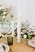 Gedeckter Hochzeitstisch mit Frühlingsblumen, trockenen Zweigen und Cylinderkerze