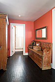 Old church pew in apricot-pink hallway with dark wooden floor