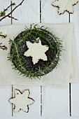 A snowflake biscuit on a spiced cake with rosemary and icing sugar