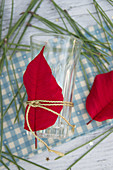 A glass decorated with poinsettias and pine needles