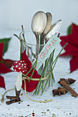 Glas mit Weihnachtsstern und Kiefernnadeln dekoriert, als Besteckhalter