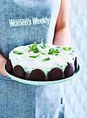 Woman holding serving platter with peppermint chocolate ice cream cake