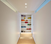 Bookcase at end of corridor with white walls and ceiling