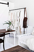 Clothes rack with white clothes next to sofa and table