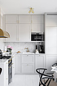 Pale grey fitted kitchen with marble splashback