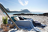 Bed linen and pillows in shades of blue on bed next to baskets on beach