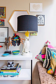Console with table lamp, bowl and books next to bench with decorative pillows