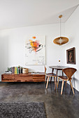 Tisch mit Designerstühlen im Zimmerecke, Lowboard und moderne Kunst an der Wand
