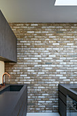 Moderne Einbauküche mit schwarzen Fronten und Backsteinwand