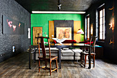 Old wooden table and chairs in renovated loft apartment with black and green walls