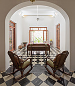 Two rocking chairs in arched doorway leading into living room with chequered floor