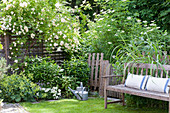 Gartenbank mit Kissen im idyllischen Sommergarten