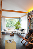 Liegestühle vor Regalwand und Designersofa in offenem Wohnraum