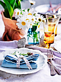 Festliches Gedeck mit blauer Leinenserviette, Schleife und Lavendelblüte