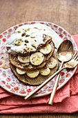 Banana pancakes made from gluten free porridge oats, banana and a free range egg topped with banana, pistachio nuts, natural yogurt and syrup