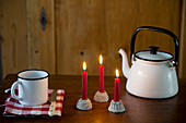 Three lit red candles in cake-shaped candle holders