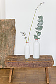 Two white vases with eucalyptus twigs on stool