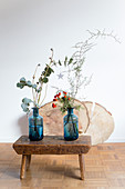 Zwei blaue Vasen mit Zweigen auf einem alten Holzschemel